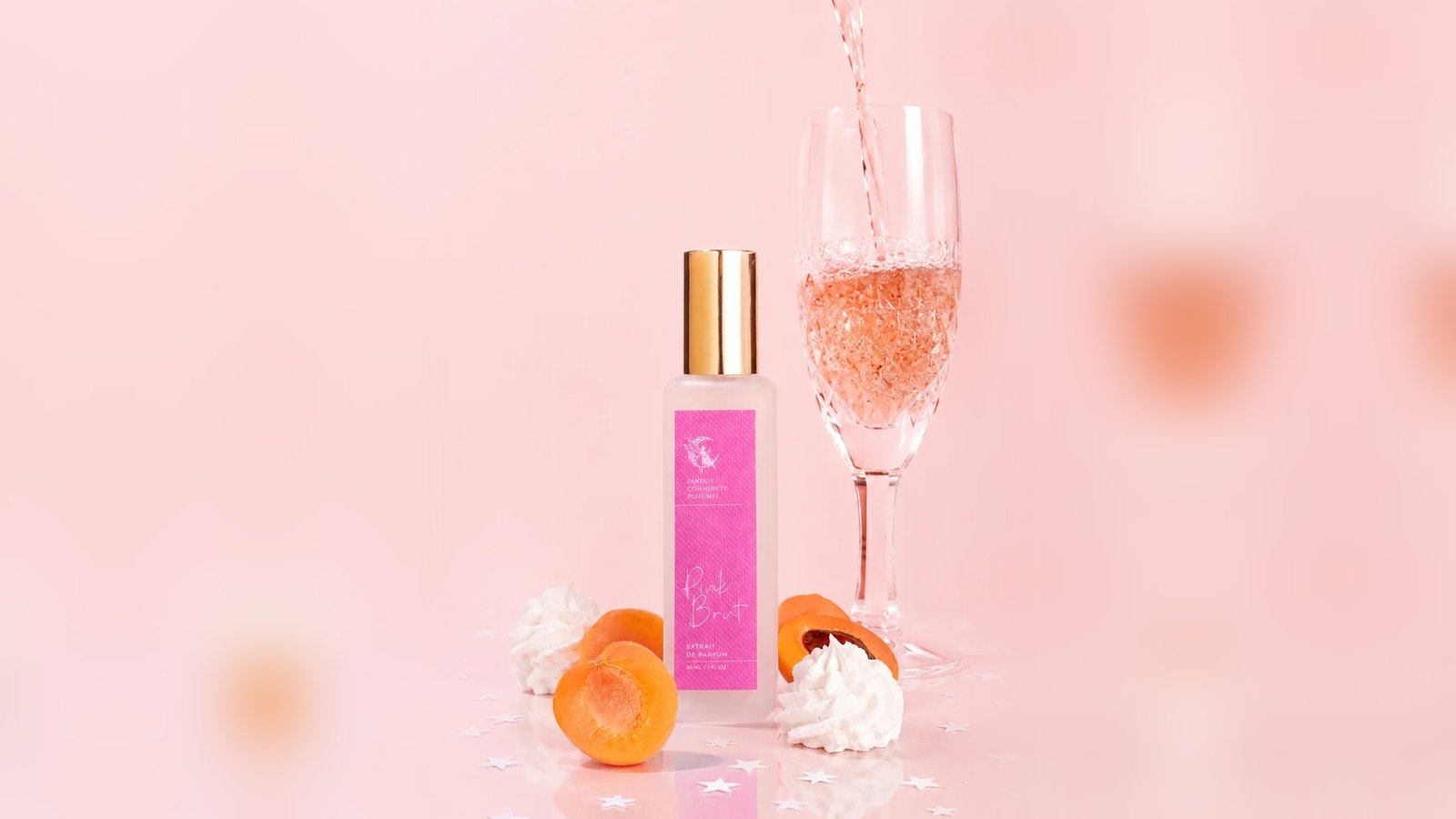 Pink Brut bottle beside a flute of pink sparkling wine being poured, with apricot halves and meringue on a pink background